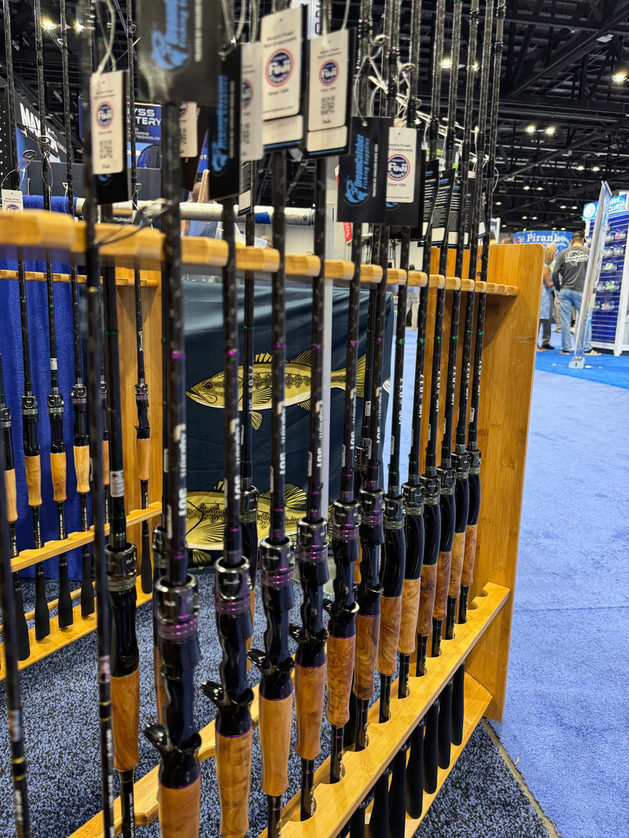 Display of carbon fiber fishing rods with wood handles on a rack at a trade show